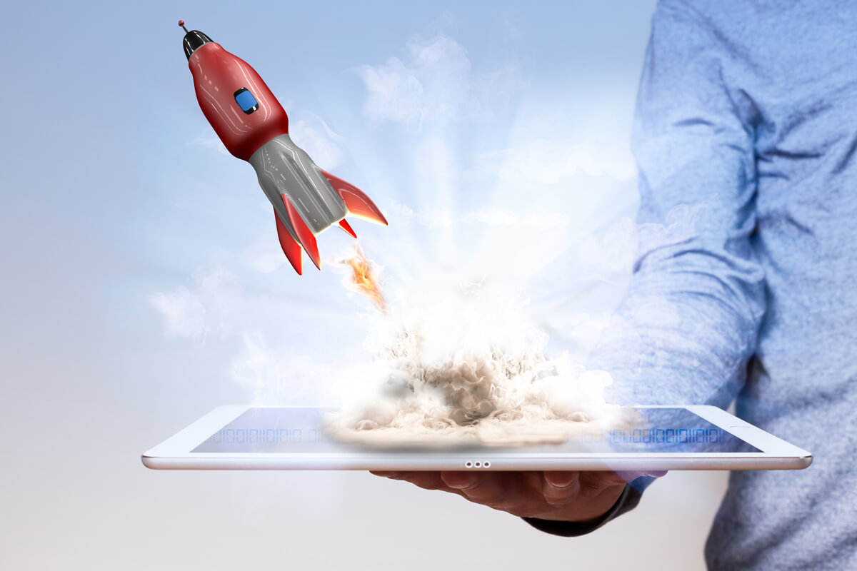 Mans hand with tablet pc and flying rocket.