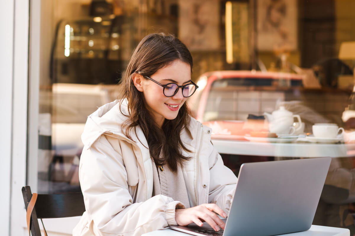 Smiling young woman using laptop while sitting in outdoor cafe